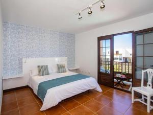 ein Schlafzimmer mit einem weißen Bett und einem Balkon in der Unterkunft Villa Verol La Vegueta Villas in Tinajo