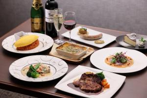 The Royal Park Hotel Kyoto Sanjo في كيوتو: طاولة مع أطباق من الطعام وزجاجة من النبيذ