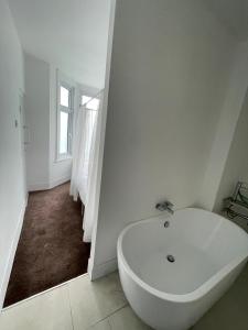 a white bath tub in a white bathroom with a window at 2 bedroom flat Wembley in London