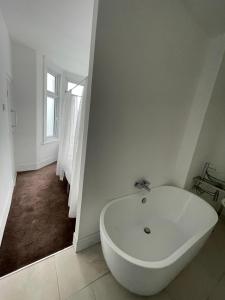 a white bath tub in a bathroom with a window at 2 bedroom flat Wembley in London