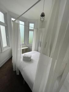 a white bedroom with a canopy bed with windows at 2 bedroom flat Wembley in London