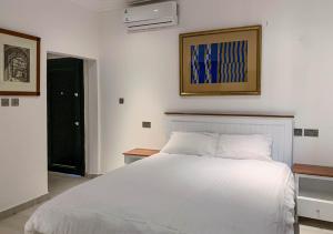 a bedroom with a white bed and a black door at Conys Guest House in Kwabenyan