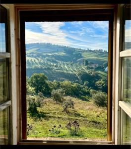 een raam met uitzicht op een veld vanaf een heuvel bij La Toscavera - I Tre Archi in Pomarance
