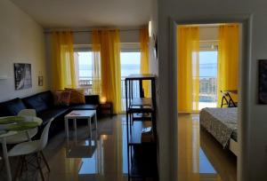 a living room with a couch and a bed and yellow curtains at Apartman Rene, 150m from the sea, panorama view, Crikvenica, Dramalj, parking in Dramalj