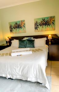 a bedroom with a large white bed with two paintings on the wall at Oasis Of Life Guest House in eMalahleni