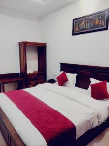 um quarto com uma cama grande e almofadas vermelhas e brancas em THE HAMIRGARH PALACE em Rājsamand