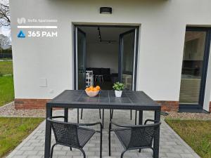 a black table with two chairs and a bowl of oranges on it at Apartament Różana Polana z Ogrodem - 365PAM in Sianozety