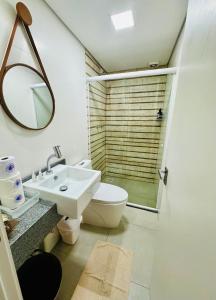 ein Badezimmer mit einem WC, einem Waschbecken und einem Spiegel in der Unterkunft Apartamento Acqua, 102 A, com vaga de garagem in Pelotas