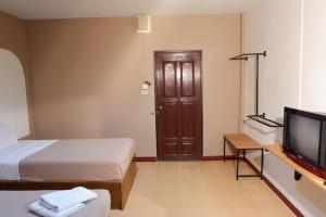 a room with two beds and a tv and a door at กิจตรงวิลล์ รีสอร์ท Kittrongvill in Ubon Ratchathani