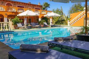 印加的住宿－Villa Selva，一座带椅子和遮阳伞的游泳池位于一座建筑旁边