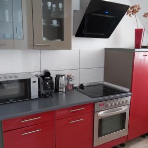 a kitchen with red cabinets and a stove top oven at Megena in Mayen +4 photos