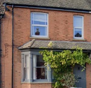 Una casa de ladrillo con dos ventanas y un arbusto en Inviting 2-Bed Character House Stamford, en Lincolnshire