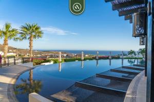 a swimming pool with palm trees and the ocean at Copala at Quivira 71 in Cabo San Lucas