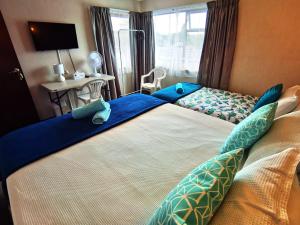a bedroom with two beds with blue pillows at Denby Golf House Tikipunga in Whangarei