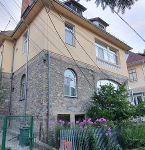 ein Steinhaus mit Blumen davor in der Unterkunft LUNA RESIDENCE SINAIA in Sinaia