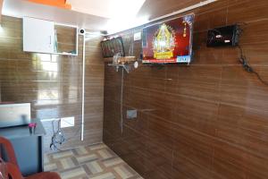 a bathroom with a shower with a television on the wall at Wisma Gokilambal Residency in Tiruvannāmalai