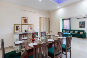 a dining room with a table and chairs and a couch at Vista Divine by VEO - Part of StayVista in Rishīkesh