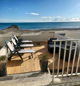 a group of lounge chairs on a deck with the beach at LES PIEDS DANS L'EAU in Palavas-les-Flots