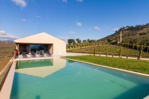 una piscina di fronte a un edificio con una casa di Luxury Vineyard Home with Infinity Pool in Douro Valley a Santa Marta de Penaguião