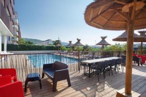 eine Terrasse mit einem Tisch, Stühlen und einem Pool in der Unterkunft Cosy Gaïa - Appt climatisé avec piscine partagée in Sète
