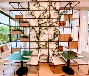 una habitación con 2 mesas y una pared con plantas en Hotel GRAND M-RCURE Itaim BiBi - Black Edition - Master Deluxe Duplex - King Studio Veranda - Dream Theater - By LuXXoR en São Paulo