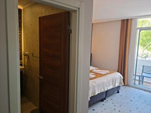 1 dormitorio con 1 cama y puerta con ventana en Tonoz Beach Hotel en Ölüdeniz