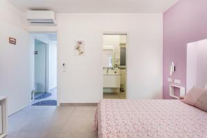 biała sypialnia z łóżkiem i łazienką w obiekcie Le Rondinelle Rooms w mieście Procida