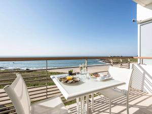 een witte tafel en stoelen op een balkon met uitzicht op het strand bij Sofitel Quiberon Thalassa sea & spa in Quiberon