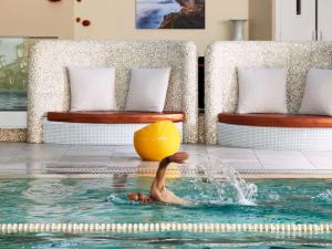 a person in a pool with a ball in the water at Sofitel Quiberon Thalassa sea & spa in Quiberon