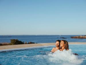 Ein Mann und eine Frau sitzen im Pool in der Unterkunft Sofitel Quiberon Thalassa sea & spa in Quiberon