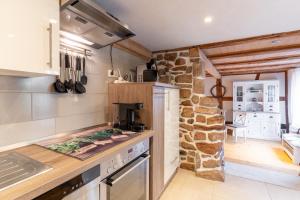 a kitchen with a stove and a stone wall at Schwarzwaldstübchen nähe Europapark in Ettenheim