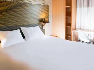 - une chambre avec un lit blanc et 2 chaises blanches dans l'établissement Ibis Hôtel Sallanches, à Sallanches