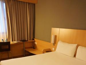 um quarto de hotel com uma cama e uma secretária em Ibis Girona em Girona
