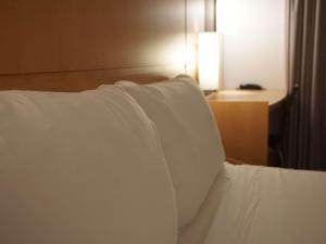 a close up of a bed with white pillows at Ibis Girona in Girona