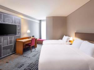 a hotel room with two beds and a desk at Ibis Ambassador Myeongdong in Seoul