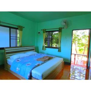 un letto in una camera con pareti e finestre verdi di Pernjai Homestay a Pua