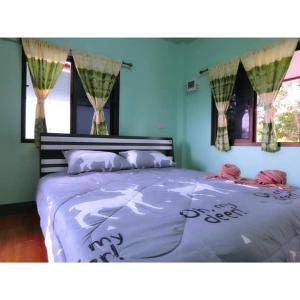 Cet appartement comprend une chambre dotée d'un grand lit, de murs bleus et de fenêtres. dans l'établissement Pernjai Homestay, à Pua