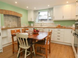 eine Küche mit einem Esstisch aus Holz und Stühlen in der Unterkunft Poppy Cottage in Beaminster
