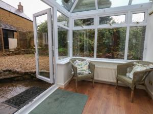 a screened in porch with two chairs and windows at Poppy Cottage in Beaminster