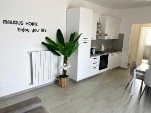 a kitchen with white cabinets and a plant in a vase at MaurusHome come a casa tua. in Fiumicino