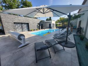 eine Terrasse mit Stühlen, einem Sonnenschirm und einem Pool in der Unterkunft Le Mas De Poujoles in Caussade