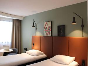 Habitación de hotel con 2 camas y mesa en ibis Bayeux Port En Bessin en Port-en-Bessin-Huppain