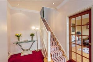 a staircase in a house with a red rug and a glass table at Hillhouse Blackhall in Edinburgh