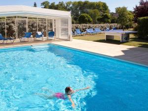 a young child swimming in a swimming pool at ibis Styles Chinon in Chinon