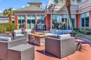 patio z wiklinowymi krzesłami i miejscem na ognisko w obiekcie Hilton Garden Inn Myrtle Beach/Coastal Grand Mall w mieście Myrtle Beach