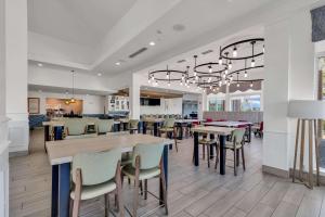 Hilton Garden Inn Myrtle Beach/Coastal Grand Mall في ميرتل بيتش: غرفة طعام مع طاولات وكراسي في مطعم