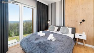 a bedroom with a large bed with a large window at Wonder Home - Domki Hillside tuż przy stoku narciarskim - na terenie kompleksu plac zabaw i zewnętrzna siłownia in Karpacz