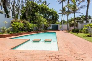a swimming pool with two benches in a yard at 77 Chaka's Cove in Ballito