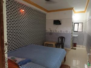 een slaapkamer met een bed en een bakstenen muur bij Goroomgo Sri Ram Guest House Puri in Puri