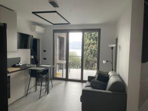 sala de estar con sofá y cocina con balcón en 3 Zimmer Apartment am Gardasee mit traumhaften Seeblick und Pool in Torri del Benaco, en Torri del Benaco